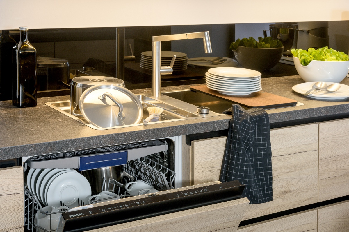 Küche mit Geschirrspüler, Edelstahlspüler und schwarzer Glasnischenrückwand