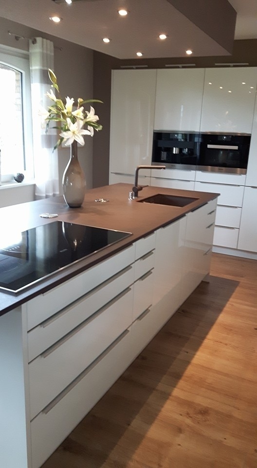 Küche mit viel Stauraum dank Schrankwand mit integrierten Geräten und Kochinsel