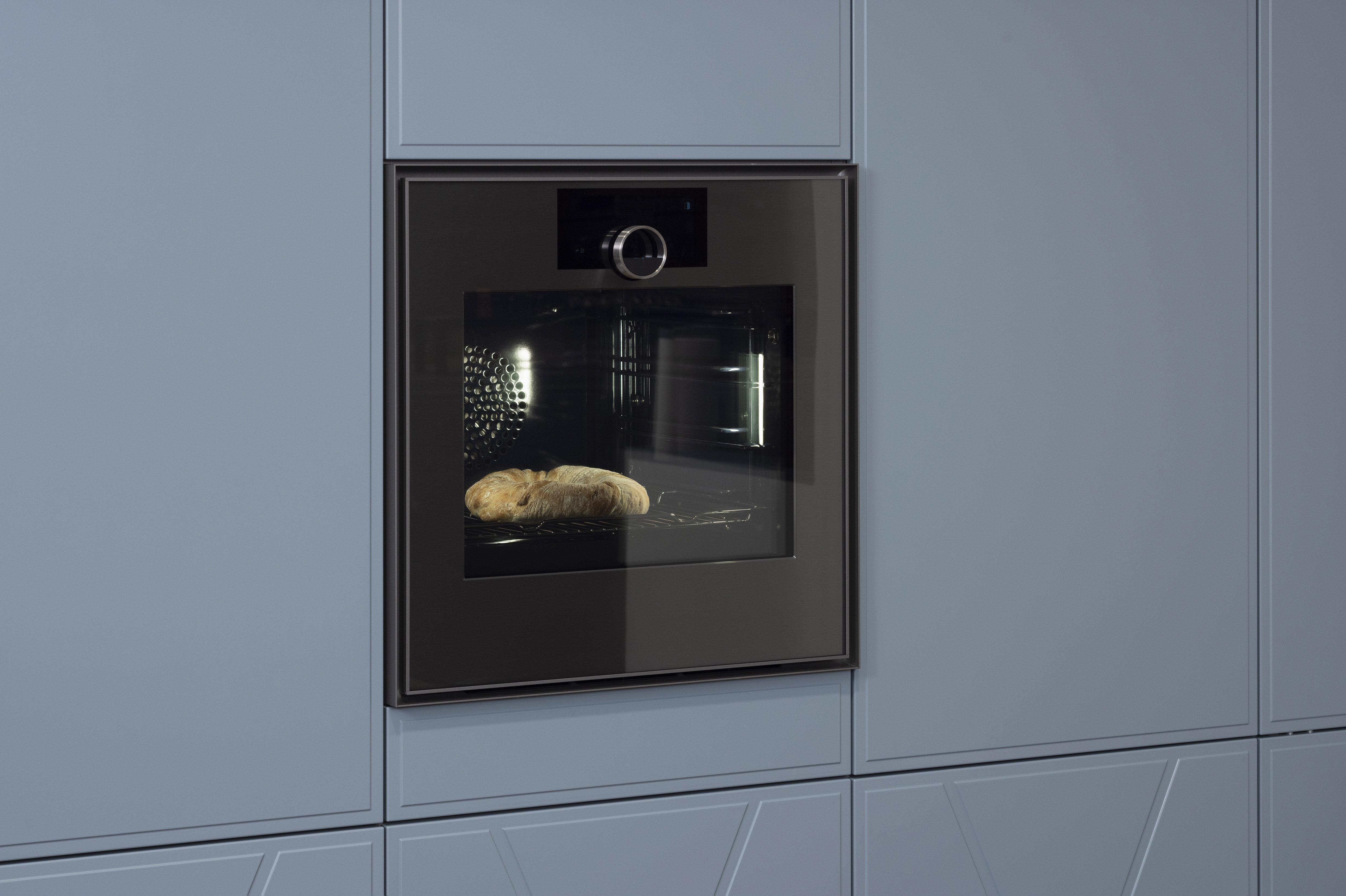 Brot backt in einem modernen Einbauofen in einer grauen Küchenwand.