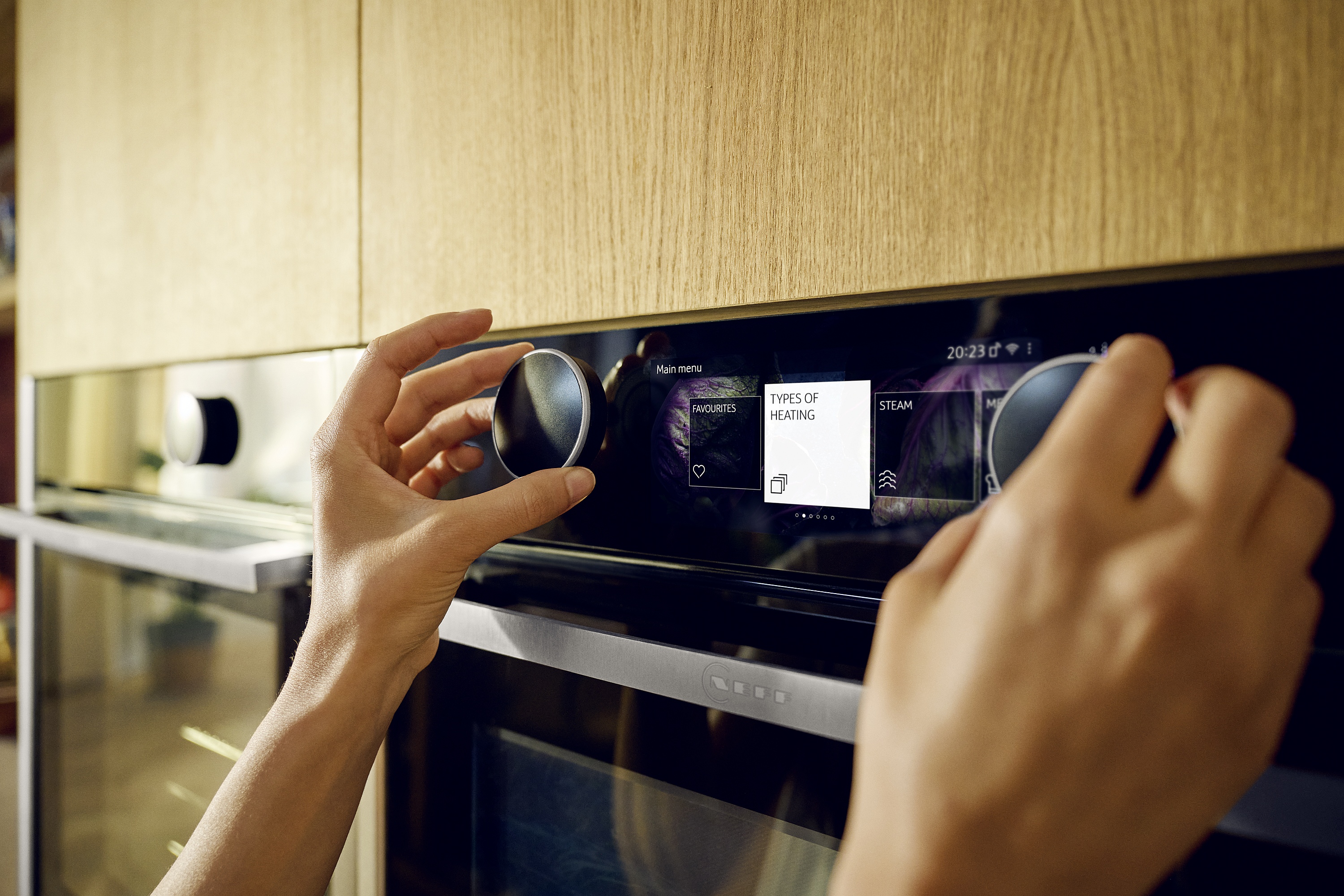 Hände bedienen zwei Twist Pad Drehknebel an Backofen