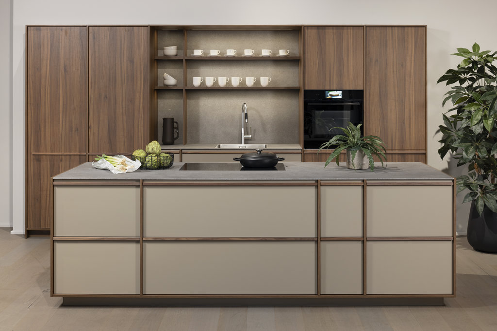 LEICHT Kücheninsel Japandi-Fronten Holzleisten auf matt lackierten Fronten sandfarben dahinter Hochschränke in Echtholz