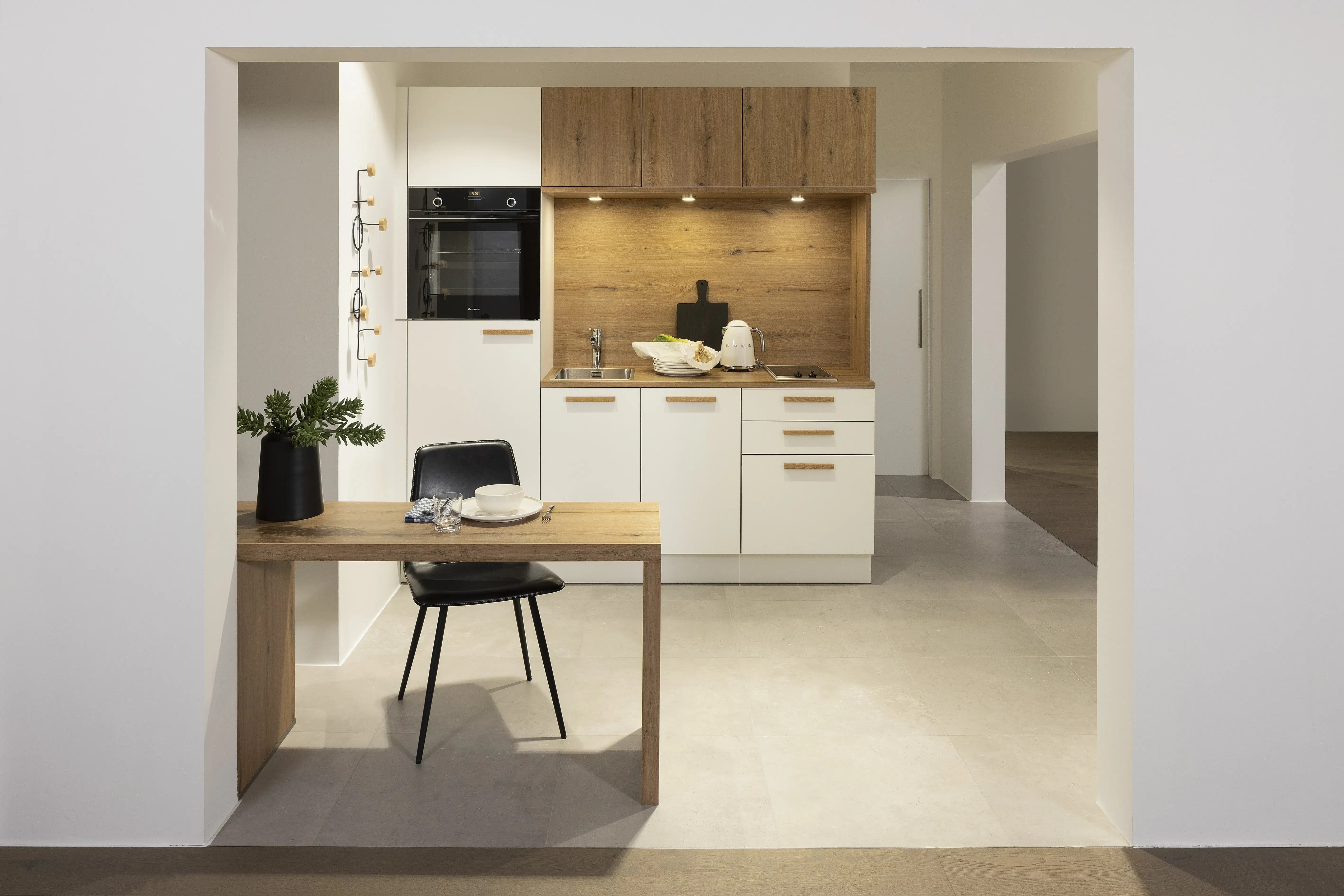 APL: Vulkaneiche NP 25 mm Front: Manhattan Vulkaneiche NB Front: Weiß Korpus: Weiß Griff: Vulkaneiche Geräte: Constructa Armatur: Nolte Spüle: Pyramis    Features: Tiny Kitchen, Einsteigerküche, Dominokochfeld 45er Spülmaschine, Holzgriffe in Frontmaterial, holzfarbene Kanten der Fronten (!), Nischenrückwand und APL gleiches Material, kleine Thekenlösung für Essen und Arbeiten, integrierter Tiny HWR.